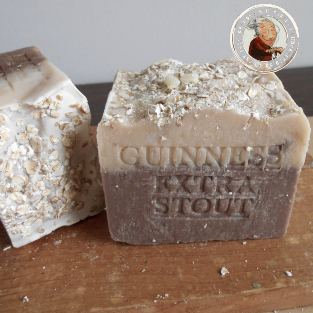 Guinness beer soap, features layers of dark brown, light brown, and beige with "STOUT GUINNESS" embossed on it. The rough-textured soap includes oatmeal pieces embedded in the beige layer at the bottom and helps soften your skin.