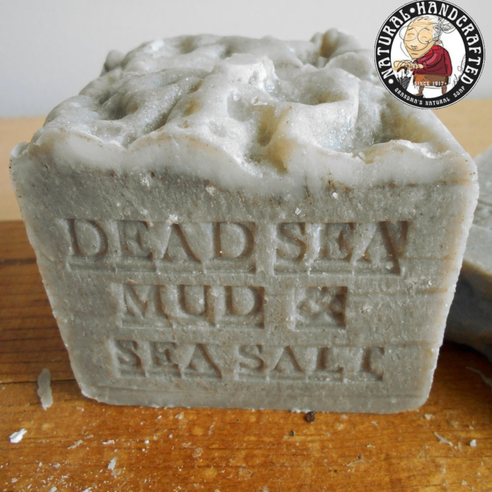 Dead Sea Mud and Sea Salt   engraved on it  here's a small logo featuring an illustration of a Grandmother. The soap has a textured surface with some speckles of sea salt